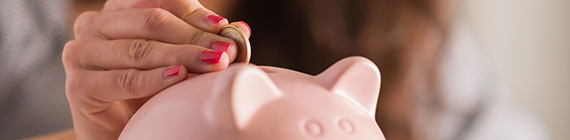 Woman putting coin in piggy bank.